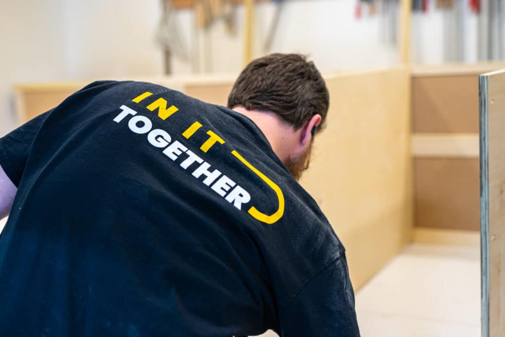 TressCo Construction team member wearing a TressCo Construction t-shirt. The t-shirt in black and says "In it together" in yellow and white letters.
